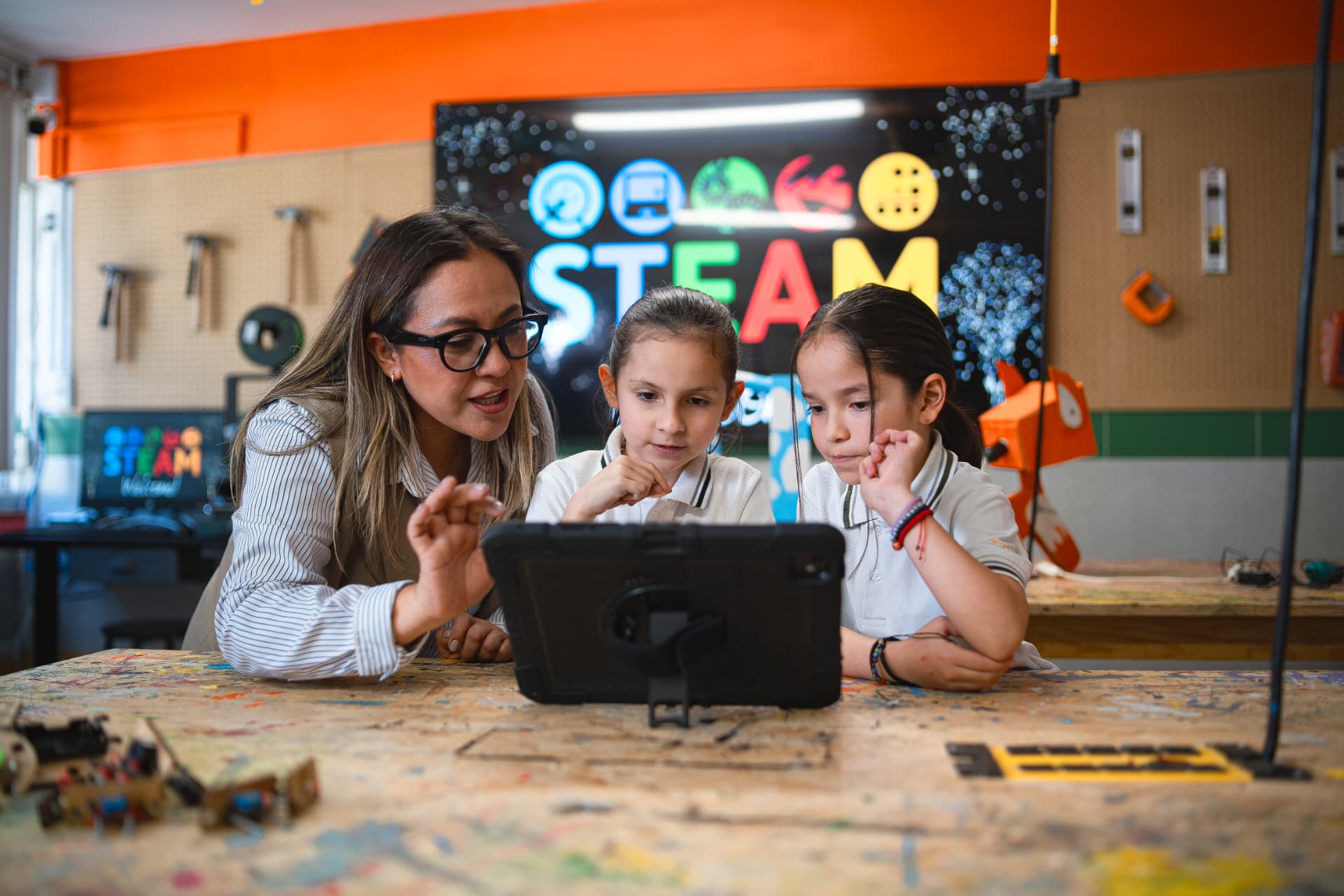 Docente guiando a dos alumnas durante una actividad con tablet