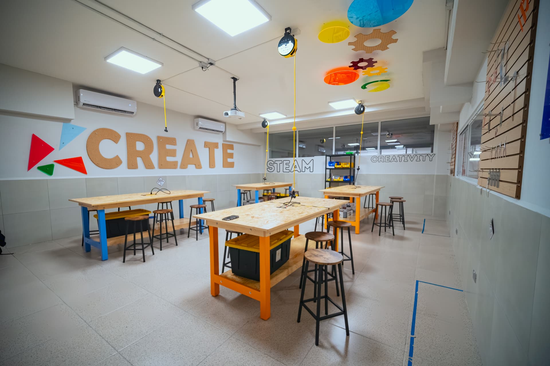 Eduu Espacio con mesas de trabajo de madera y decoración STEAM en muros y techo