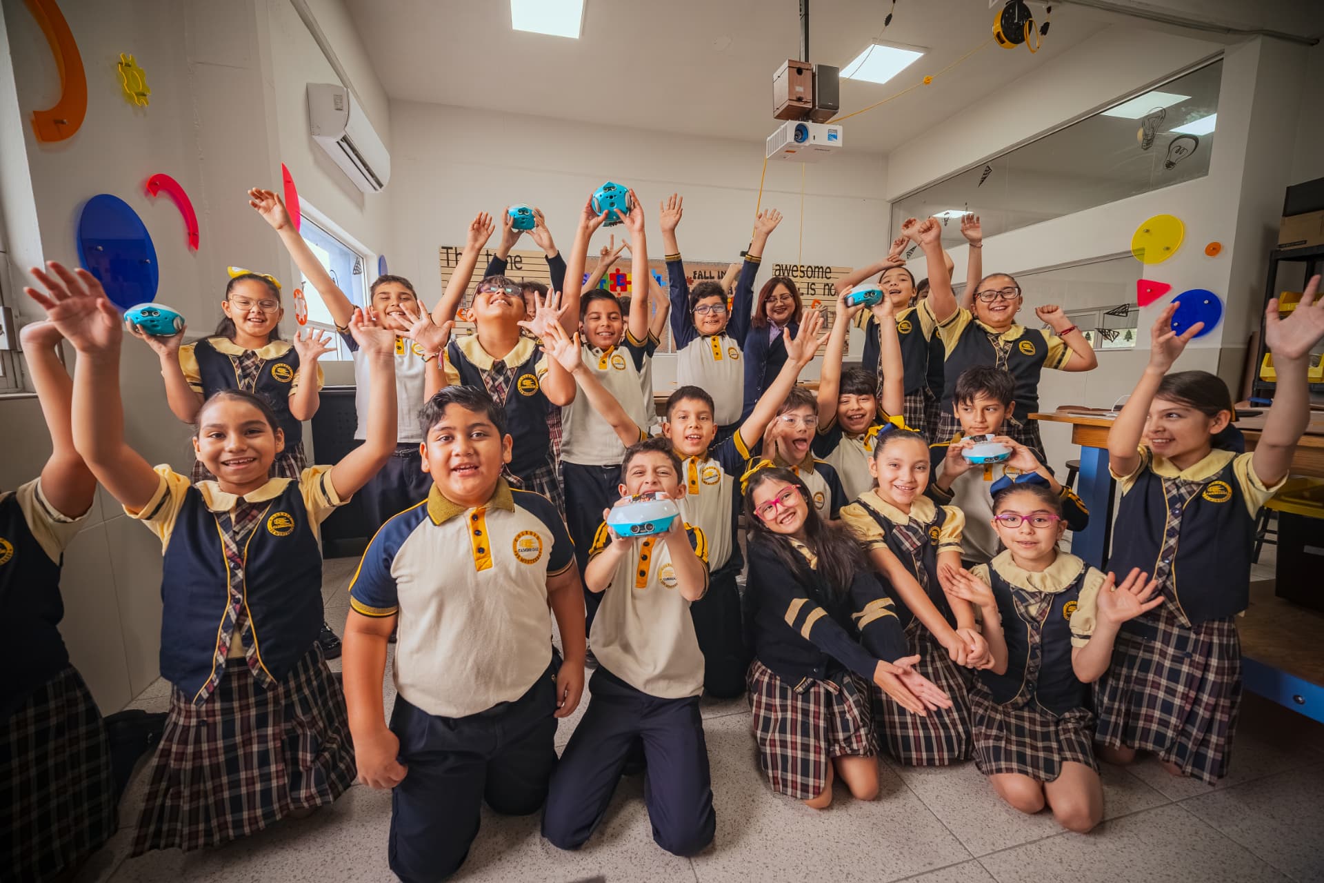 Grupo de estudiantes celebrando con robots educativos en su aula