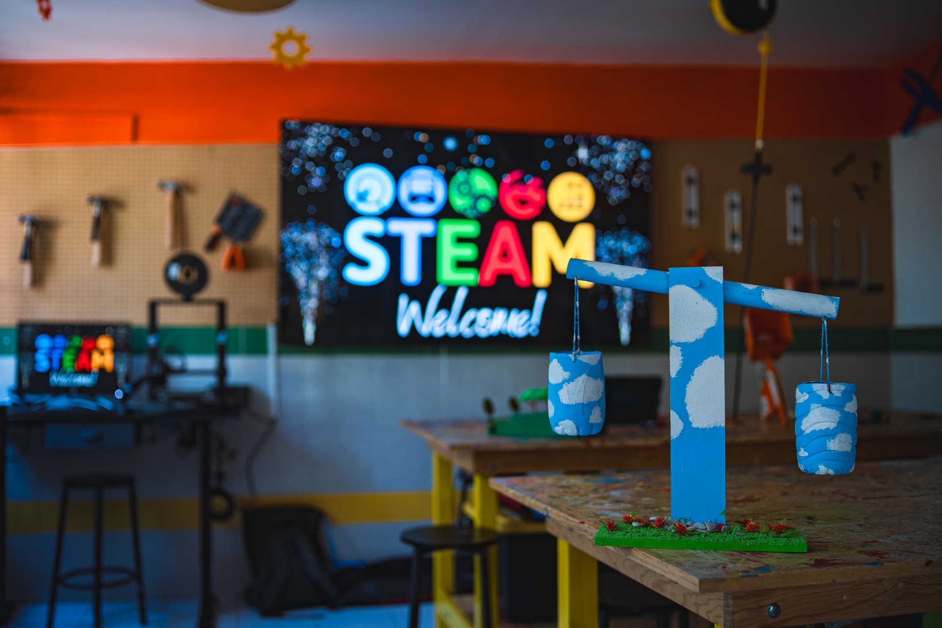 Proyecto de balanza hecho por alumnos frente a una pantalla STEAM